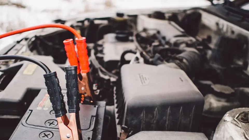 Jumper leads connected to a car battery under an open bonnet