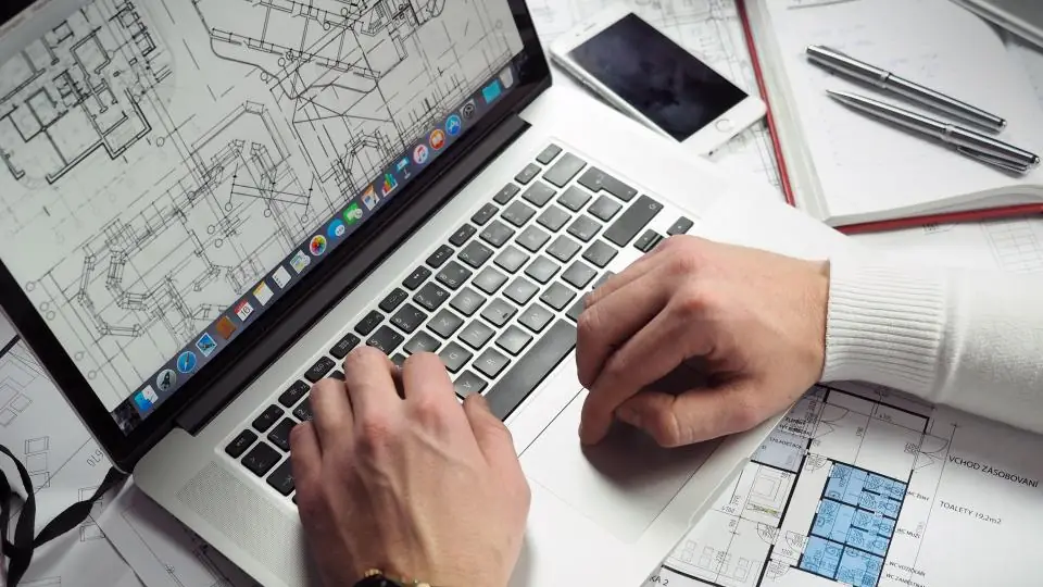 Engineer reviewing technical drawings on a laptop