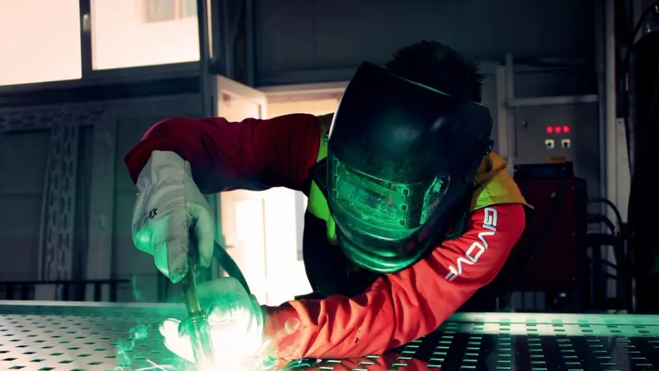 Welder in a protective helmet with sparks flying from the weld