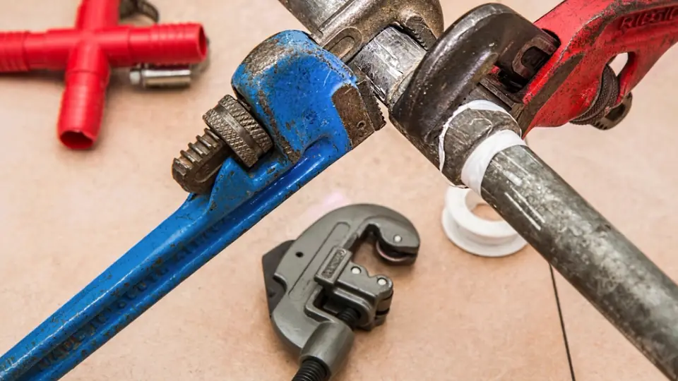 Pipe wrenches and plumbing fittings on a workbench