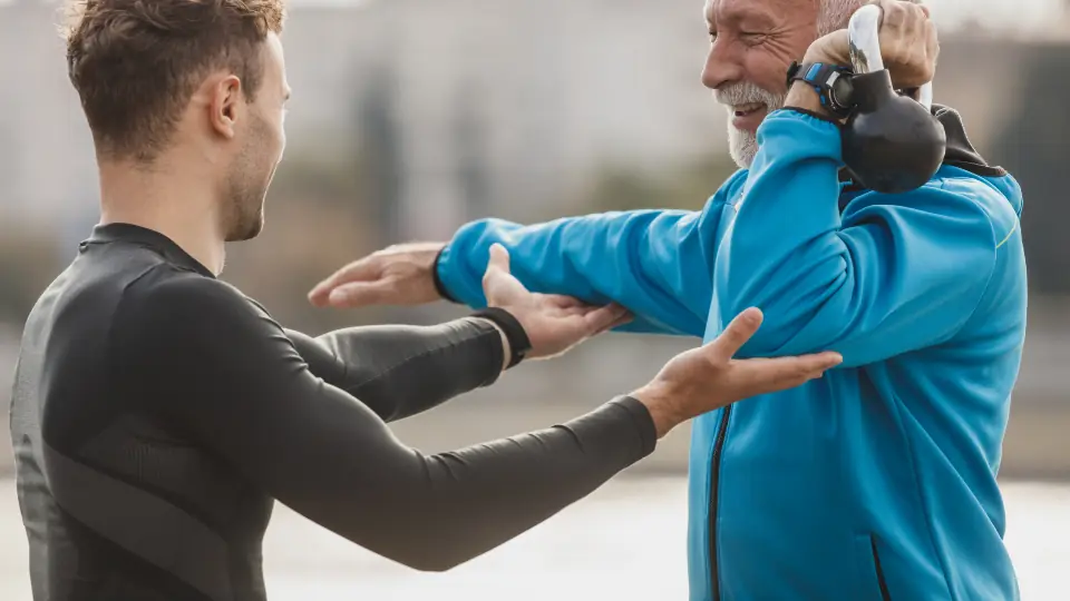 Support worker helping an older man exercise outdoors