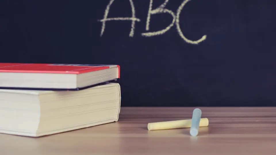 Chalkboard with ABC written above a stack of school books