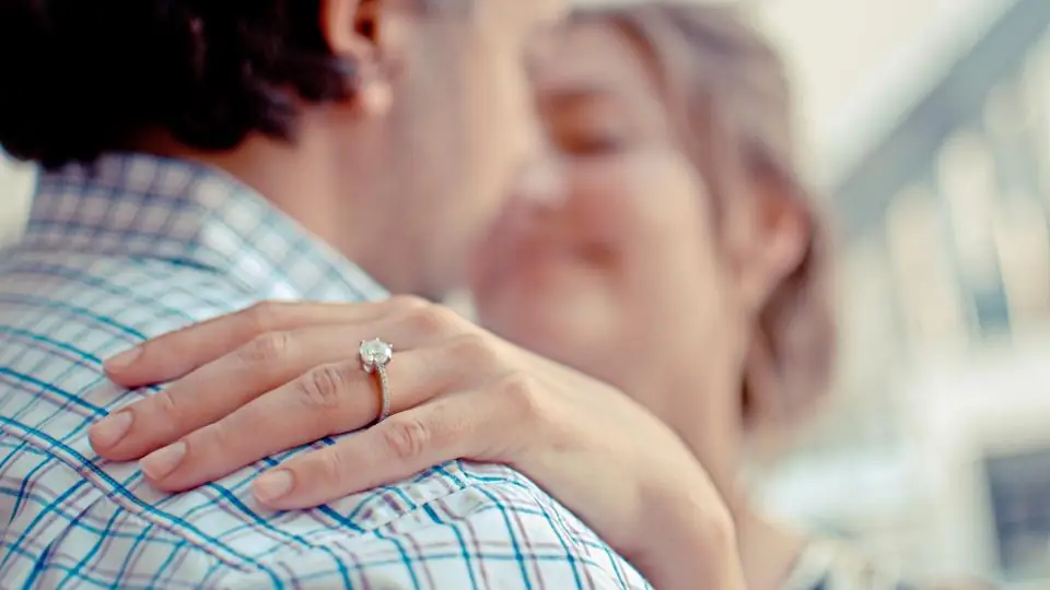 Engaged couple embracing, with an engagement ring on her hand