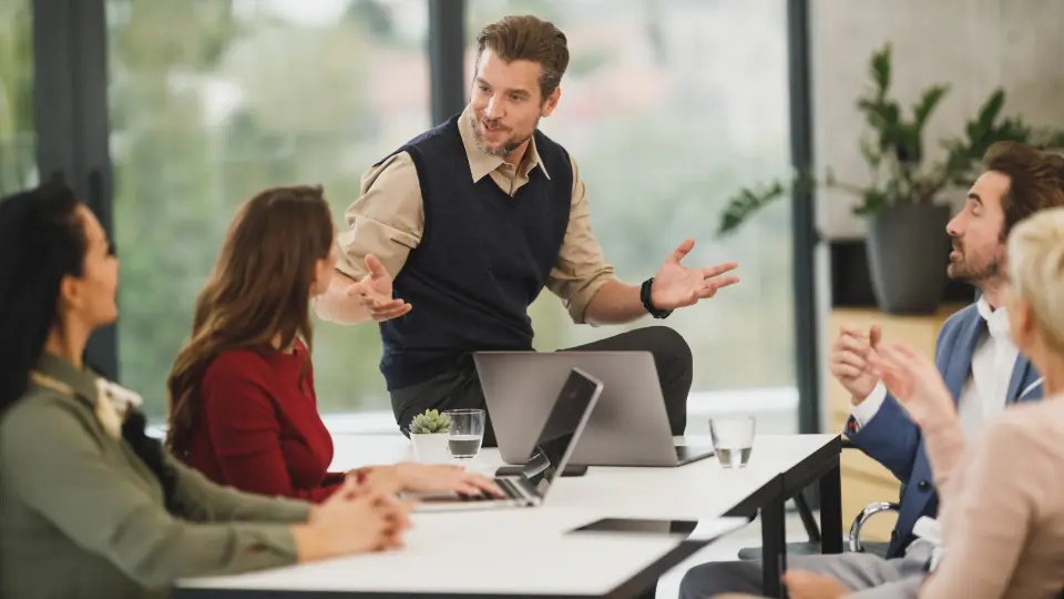 Manager leading a team meeting around a table in an office