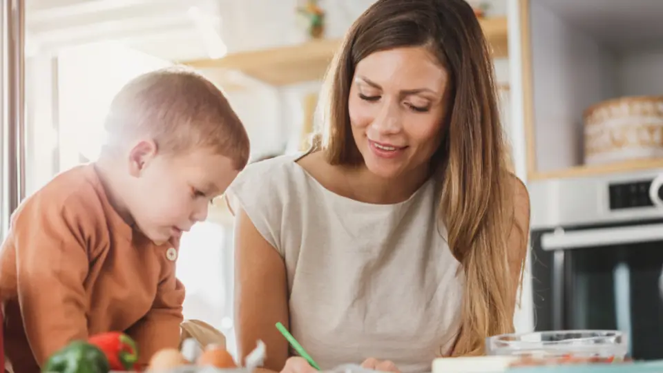 Mother helping her young son with schoolwork at the kitchen table
